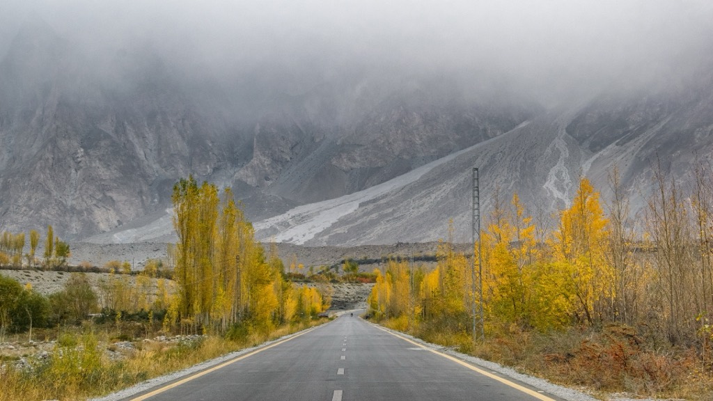Karakoram Highway passing autumn poplars below the Passu Cones